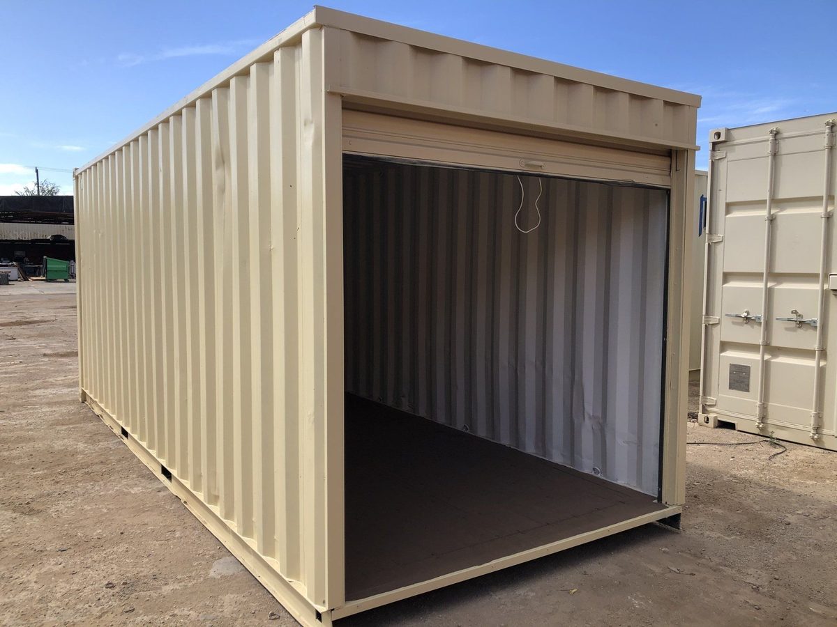 Shipping container with a wide roll-up door open, on a desert lot